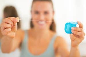 Closeup on happy young woman showing dental floss