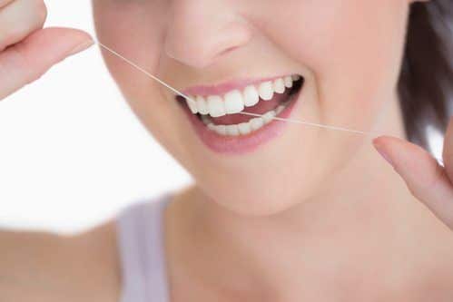 Woman using dental floss against white background