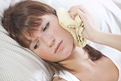 A woman lying in bed with a toothache