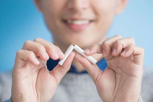 man breaking cigarette and smiling