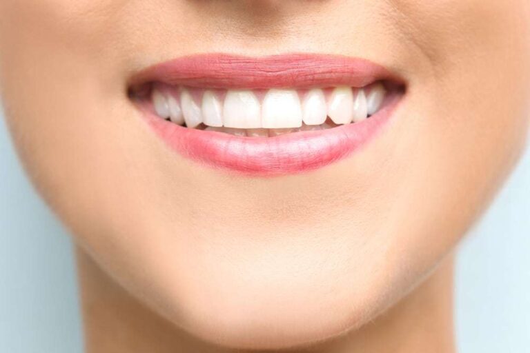 Young beautiful woman with healthy teeth smiling on light background, close up