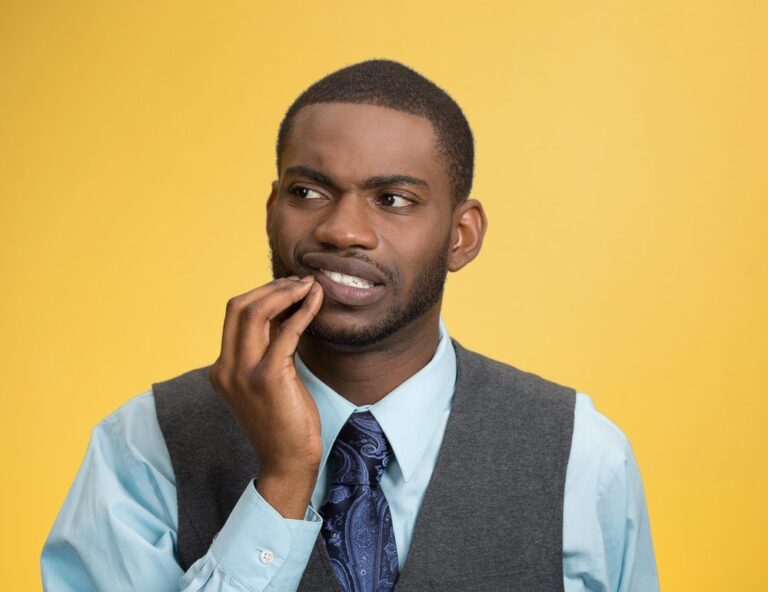 Closeup portrait of young man in shirt, tie, and vest, touching face having bad pain, tooth ache