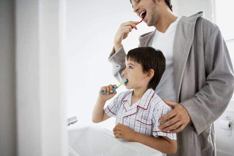 Father and son brushing teeth together in bathroom