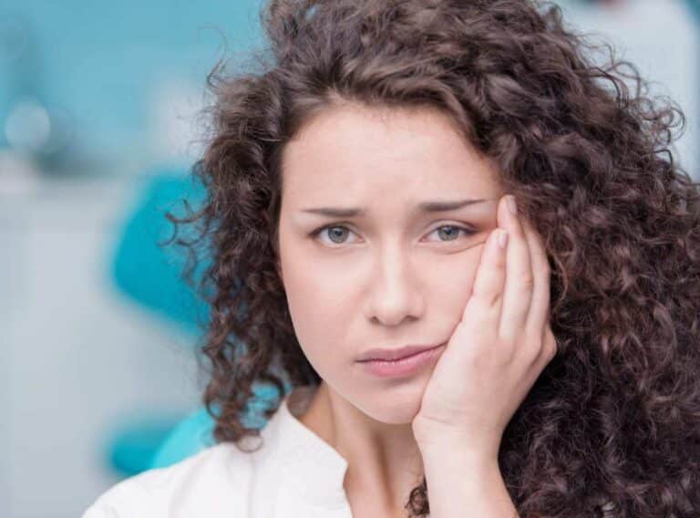 Young Woman Holding a Hand to Her Cheek, in Pain from Toothache