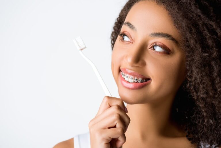 Young-woman-with-braces-smiling-holding-toothbrush