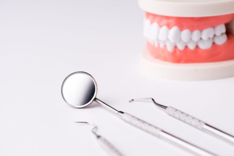 Dental-tools-on-white-surface-dentures-in-background