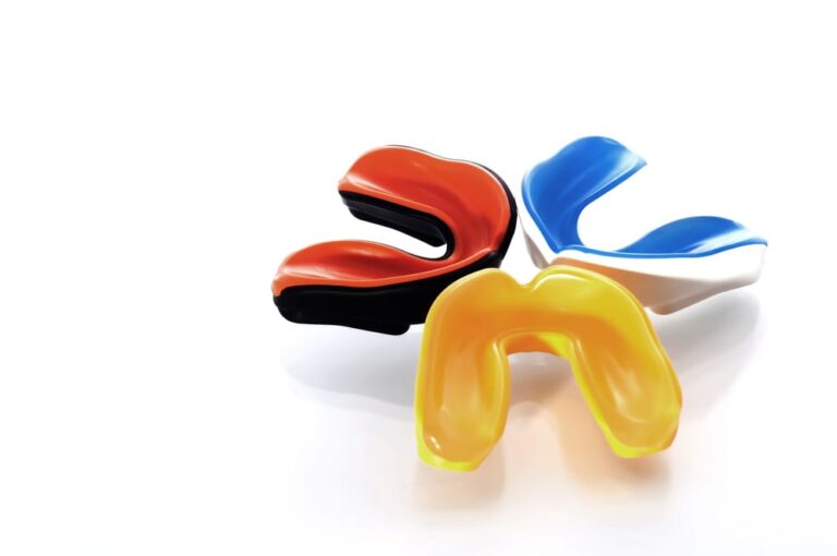 Three-colorful-mouthguards-on-white-surface