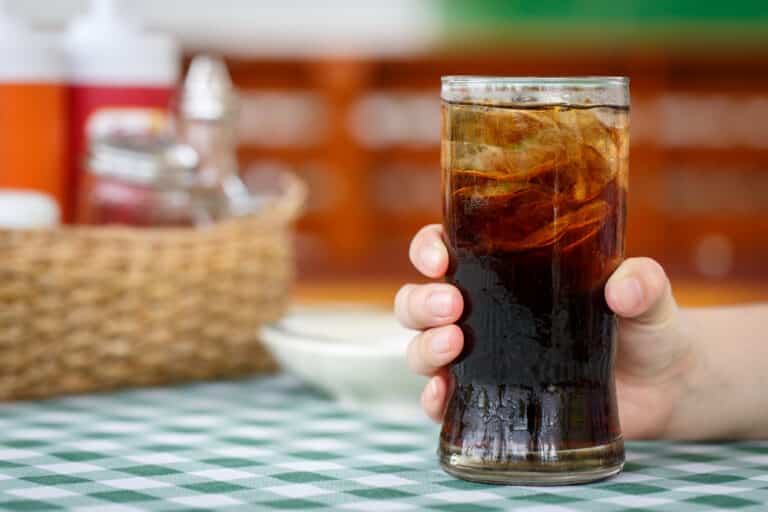 Hand grasping glass of cold cola soda