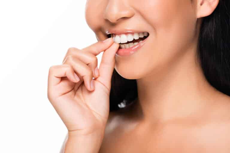 Close-up of asian woman touching thumb to white smile