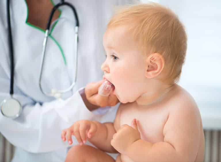 Doctor brushing baby teeth with finger