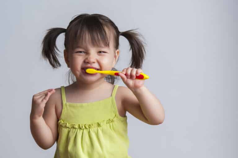 Little girl brushing her teeth with a smile