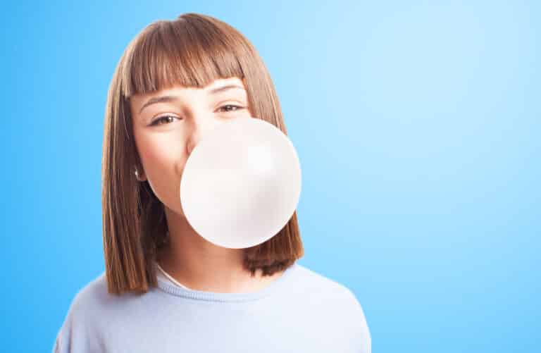 Girl chewing gum, blowing bubble