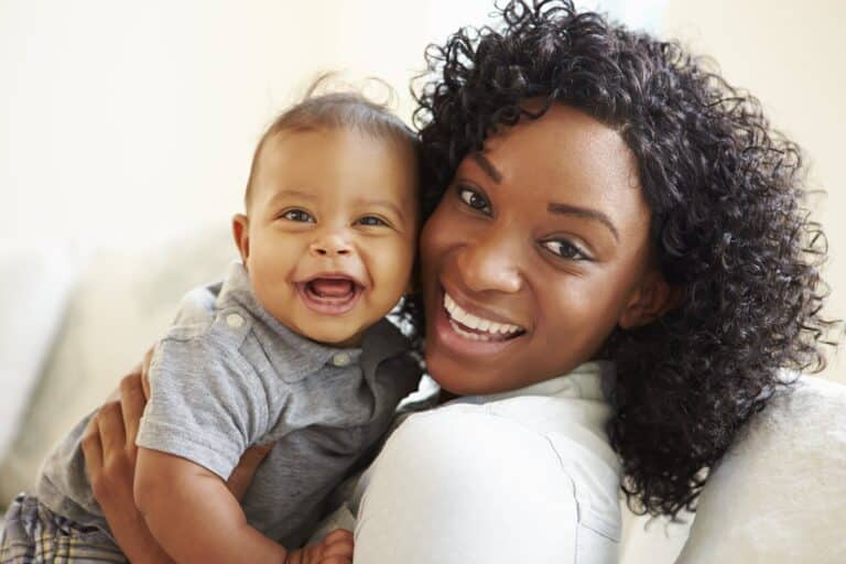 Young mother holding baby, both smiling