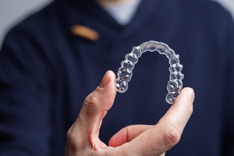 Close-up of Invisalign aligner held up by dental professional
