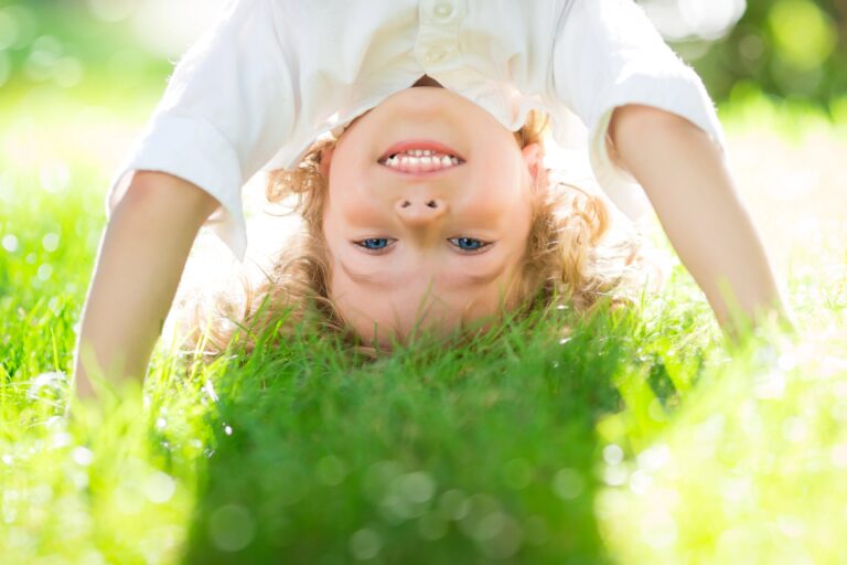 Child upside down in grass, smiling